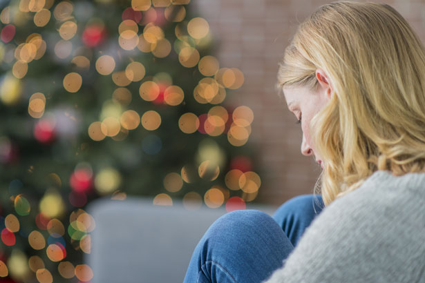 Person sitting alone next to Christmas tree